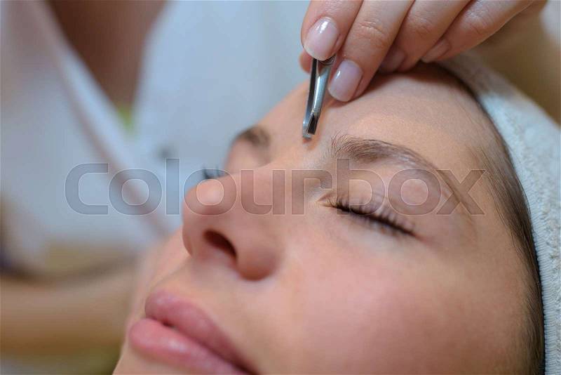 Grooming eyebrows in a beauty salon, stock photo