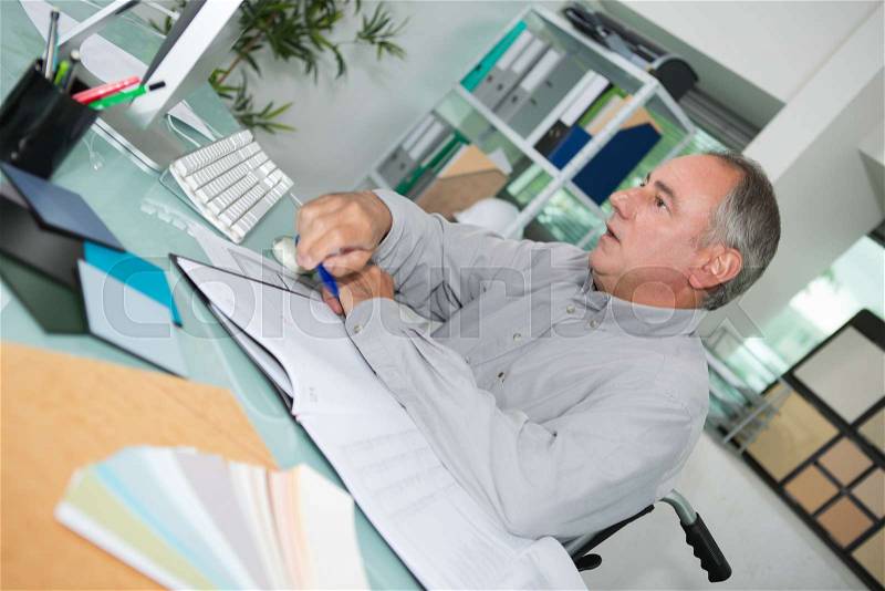 Middle-age businessman with eyeglasses working on computer in office, stock photo