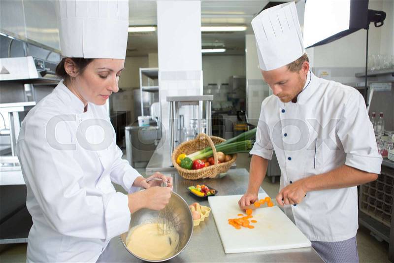 Happy chefs and assistant in apron working at restaurant kitchen, stock photo