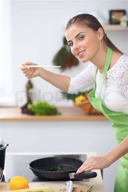 Young woman housewife cooking in the kitchen. Concept of fresh and healthy meal at home, stock photo