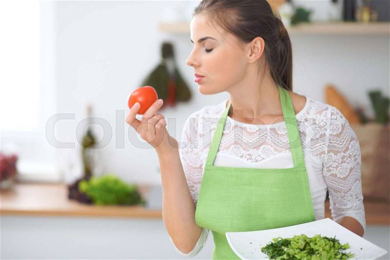 Young woman housewife cooking in the kitchen. Concept of fresh and healthy meal at home, stock photo