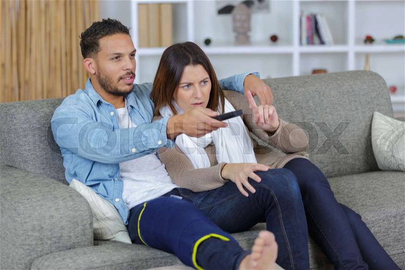 Injured boyfriend and girlfriend watching tv at home, stock photo