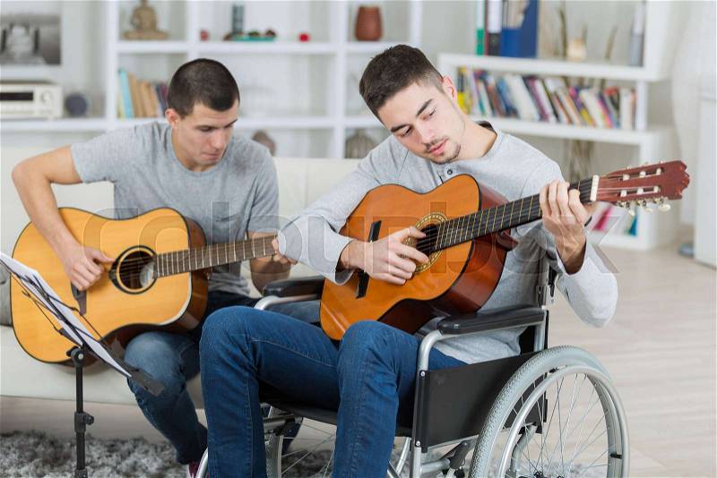 Handicapped teenager and friend playing the guitar, stock photo