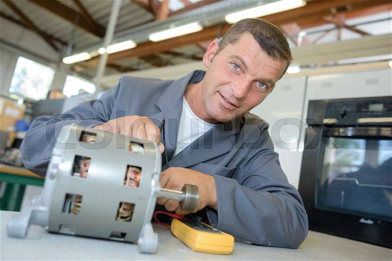 Portrait of repairman testing cylindrical component, stock photo