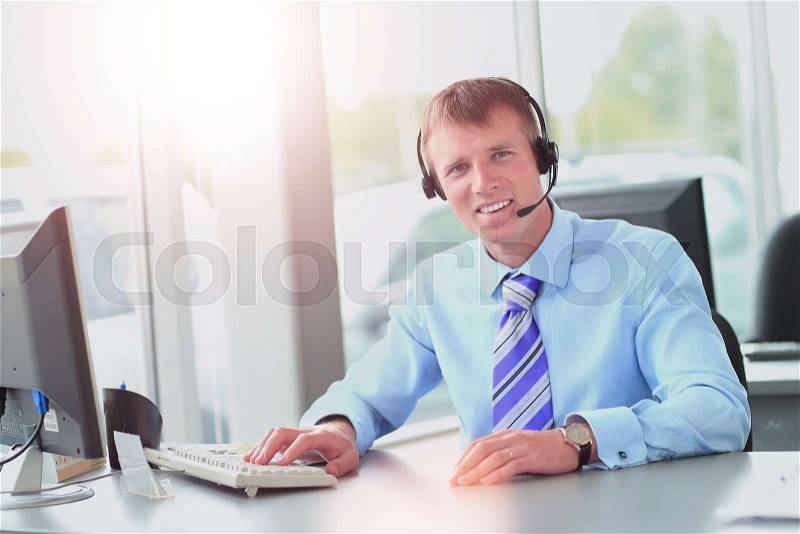 Happy young man working at callcenter, using headset, stock photo