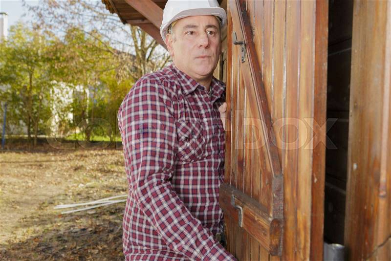 Senior man by wooden shed, stock photo
