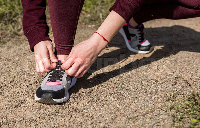 Cropped shot of young woman lacing shoe before jogging, stock photo