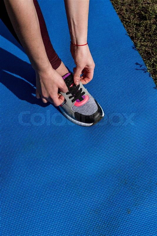 Cropped shot of young woman lacing shoe before workout, stock photo