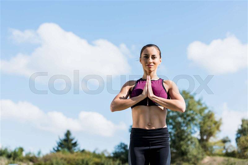 Happy woman in Prayer Pose practicing yoga outdoors, stock photo