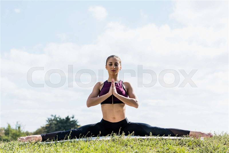 Attractive woman in seated pose practicing yoga outdoors, stock photo