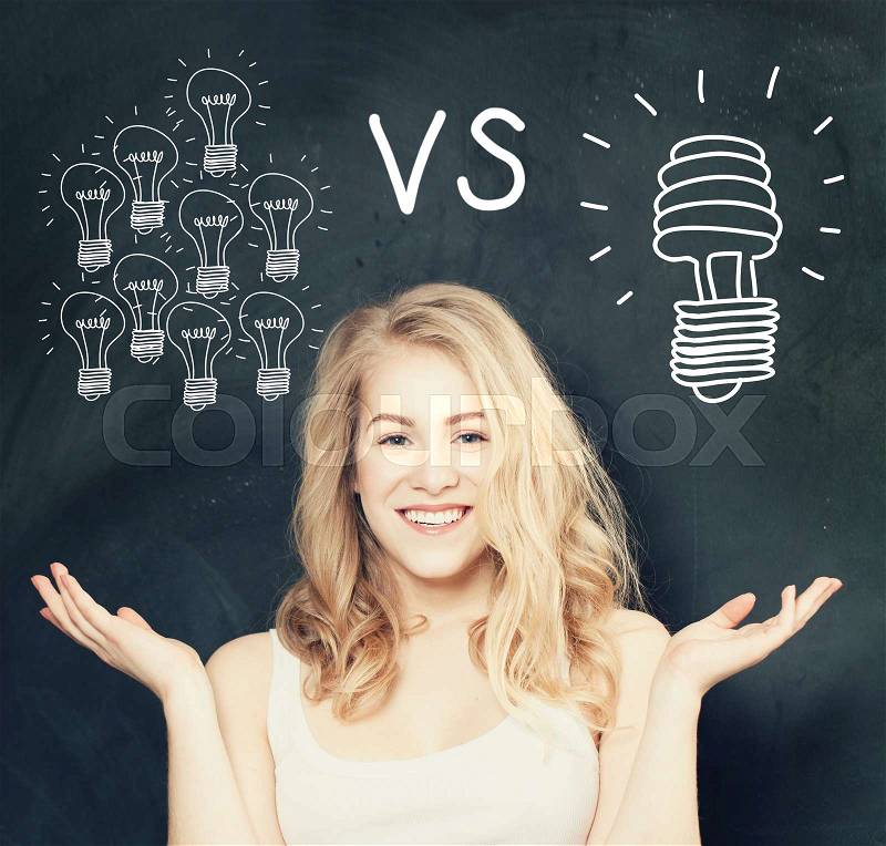 Happy Woman with traditional and energy efficient light bulbs on Blackboard Background. Energy saving concept. , stock photo