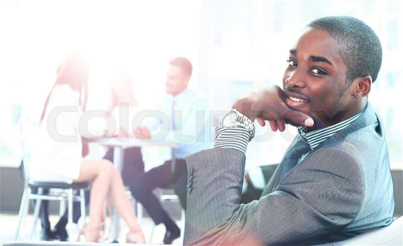 Portrait of smiling African American business man with executives working in background, stock photo