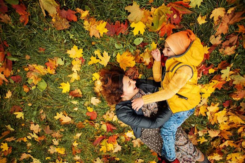 Happy Autumn Family in Fall Park Outdoor. Cheerful Mother and Child Boy having Fun Outdoors, stock photo
