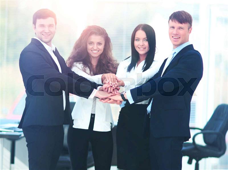 Group of business people piling up their hands together in the workplace, stock photo