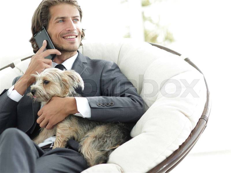 Successful businessman holds his dog and pet and talks on the smartphone, stock photo