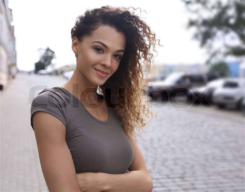 Young woman with afro hairstyle smiling in urban background, stock photo