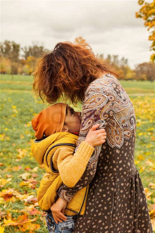 Happy Autumn Family. Cute Mother and Son Hugging in Fall Park Outdoors, stock photo