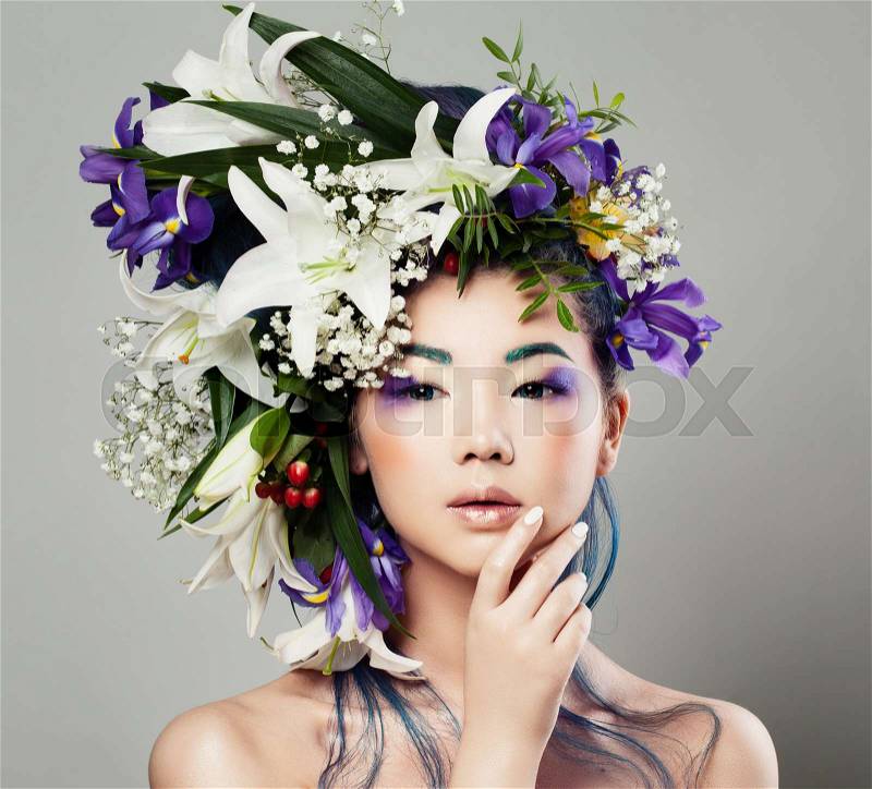 Young Cute Asian Model Woman with Blossom Flower Hairstyle and Perfect Makeup. Nice Girl with Lily and Iris Flowers, stock photo