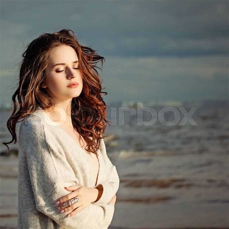 Beautiful Healthy Woman Fashion Model Resting on Blue Sea and Sky Background Outdoors, stock photo