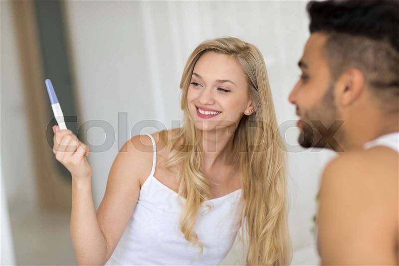Young Couple Sitting In Bed, Happy Smile Woman Show Excited Surprised Man Positive Pregnancy Test Lovers Bedroom, stock photo