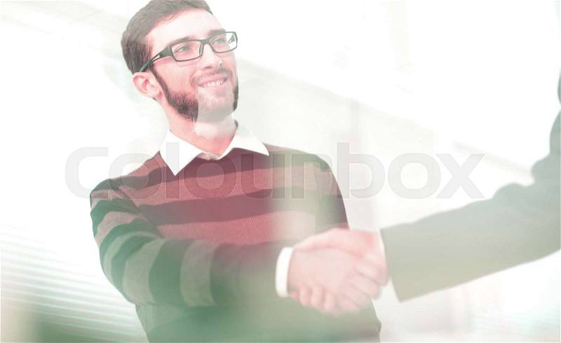 Two men shaking hands and looking at each other with smile, stock photo