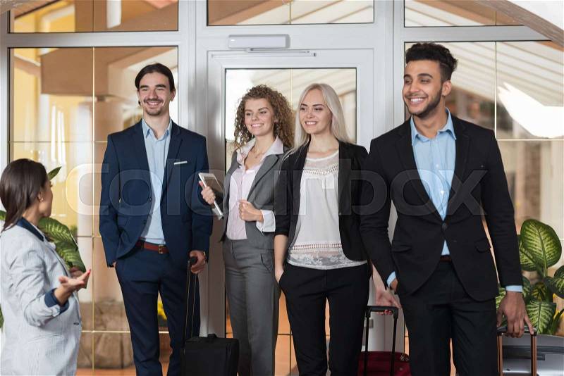 Hotel Administrator Welcome Business People In Lobby, Mix Race Businesspeople Group Guests Arrive Entrance With Suitcase, stock photo