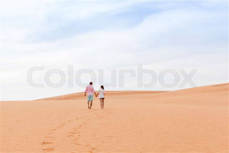 Young Man Woman Walking In Desert Couple Girl And Man Hold Hands Back Rear View Sand Dune Landscape Nature Background, stock photo