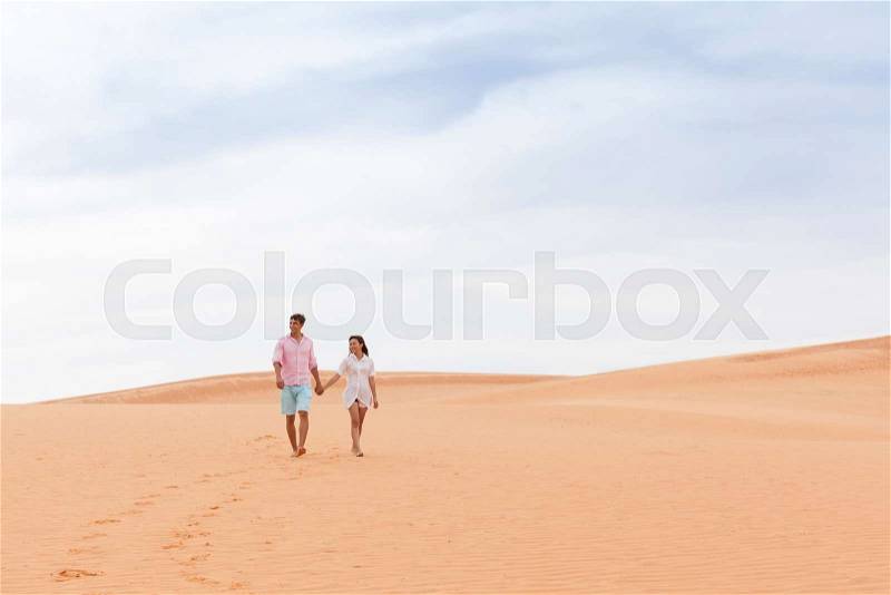 Young Man Woman Walking In Desert Couple Girl And Man Hold Hands Sand Dune Landscape Nature Background, stock photo