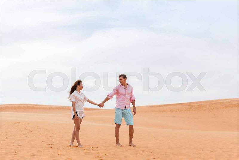 Young Man Woman Walking In Desert Couple Girl And Man Hold Hands Sand Dune Landscape Nature Background, stock photo