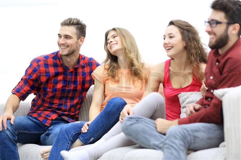 Group of cheerful friends sitting on the couch in the living room, stock photo