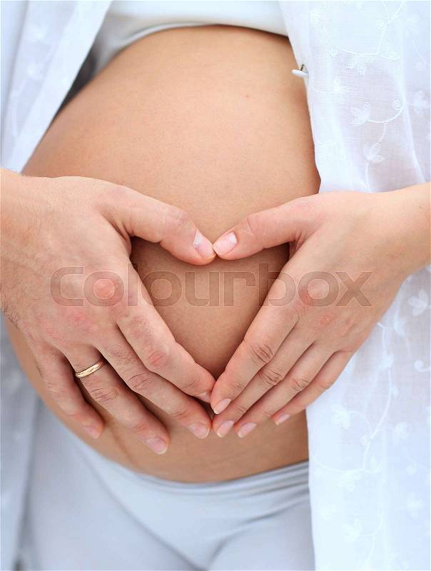 Husband and pregnant wife with folded hands in the shape of a heart on his tummy.concept of family, stock photo