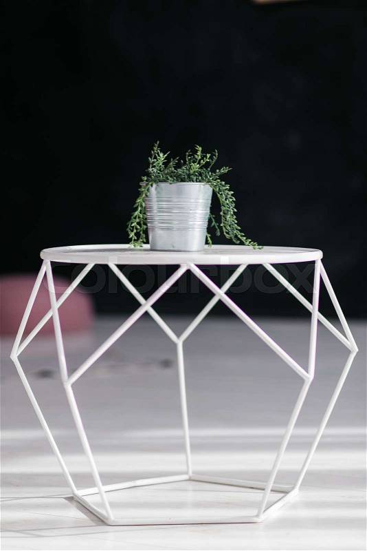 Loft design geometric white table with flower in bucket pot isolated on black background. Modern interior concept, stock photo
