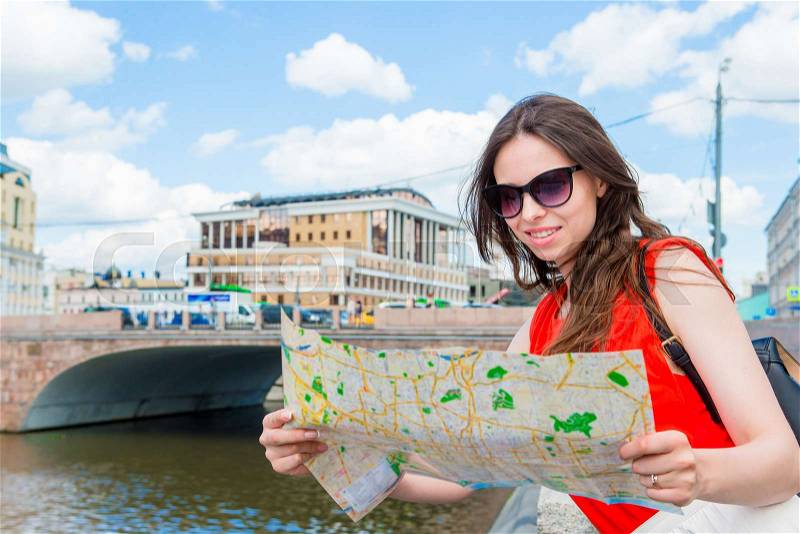 Happy young woman with a city map in Europe. Travel tourist woman with map outdoors during holidays in Europe, stock photo