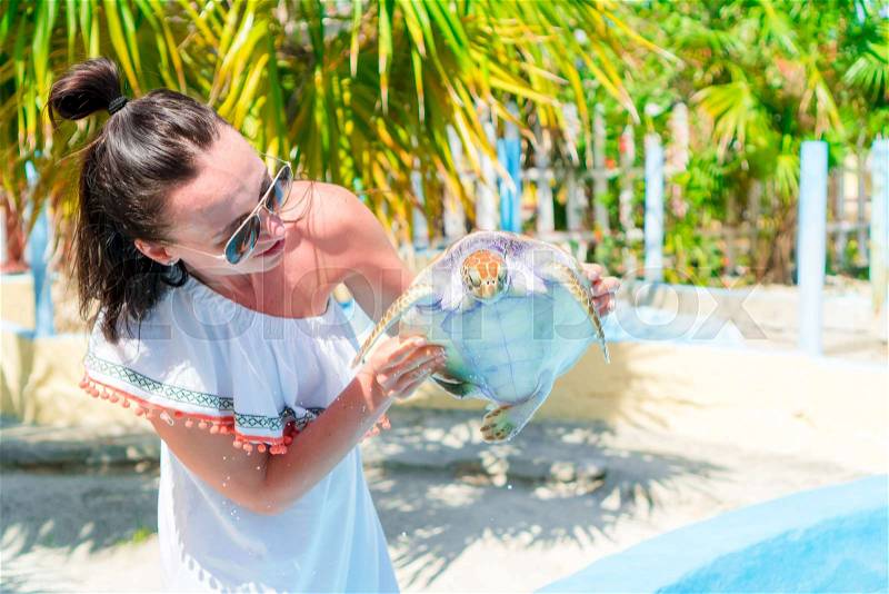 Tourist woman with sea turtle in the hands in exotic reserve, stock photo