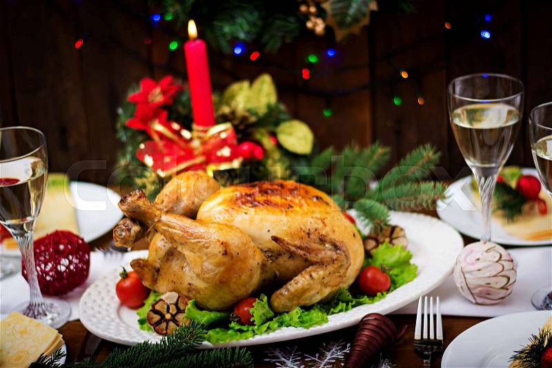 Baked turkey or chicken. The Christmas table is served with a turkey, decorated with bright tinsel and candles. Fried chicken, table. Christmas dinner, stock photo