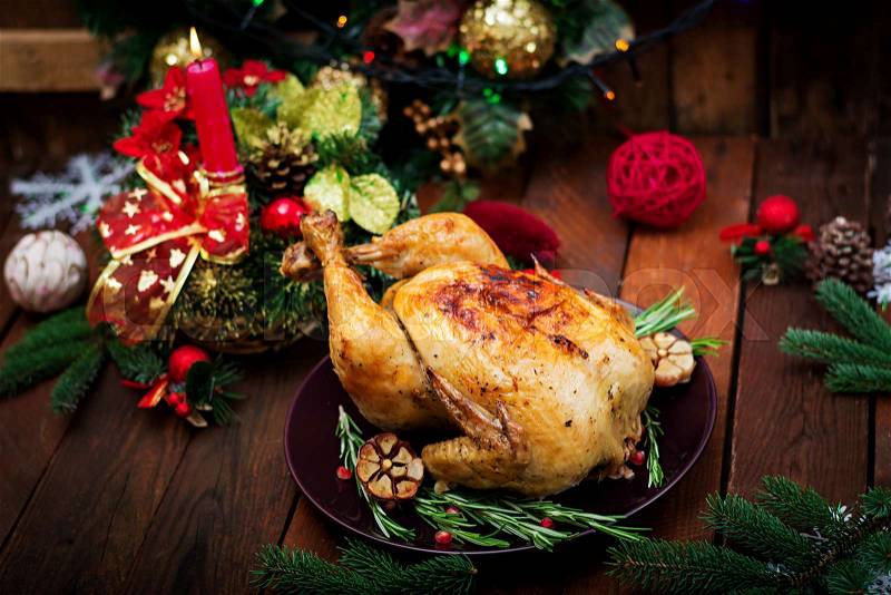 Baked turkey or chicken. The Christmas table is served with a turkey, decorated with bright tinsel and candles. Fried chicken, table. Christmas dinner, stock photo
