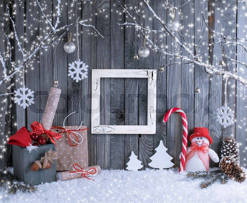 Christmas interior with snowman, photo frame, decorative branches, presents and candy canes on wooden planks background. New Year winter composition. , stock photo