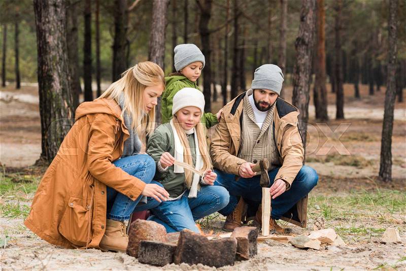 Beautiful young family making campfire in autumn forest, stock photo
