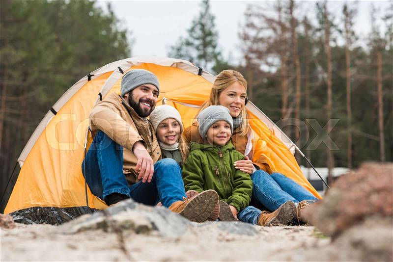Happy family sitting near camping tent on nature, stock photo