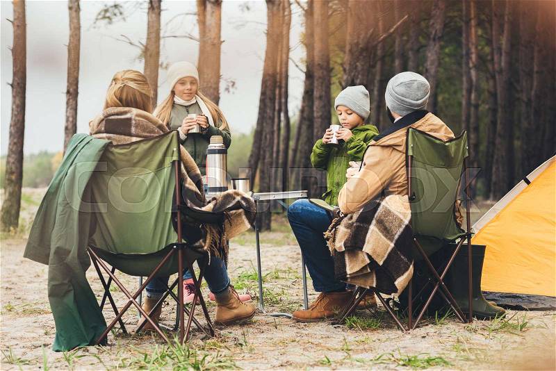 Beautiful family drinking hot tea while having camping trip, stock photo