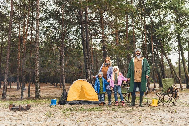 Young happy family camping in forest on rainy autumn day, stock photo
