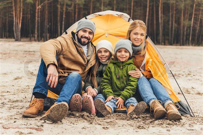 Beautiful young family sitting next to camping tent, stock photo