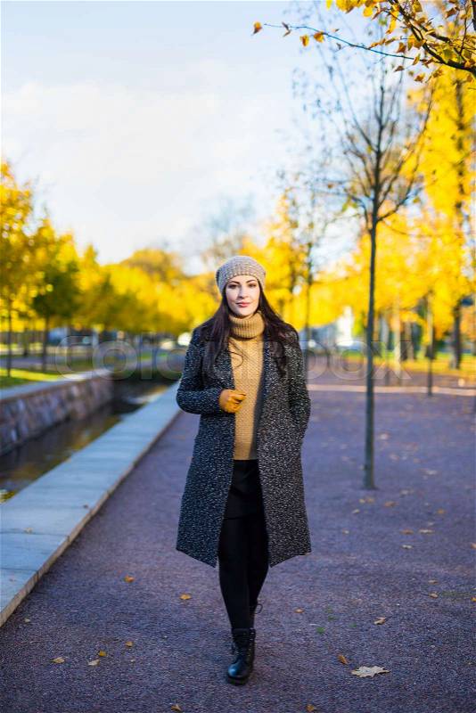 Young attractive woman in warm clothes walking in autumn park, stock photo