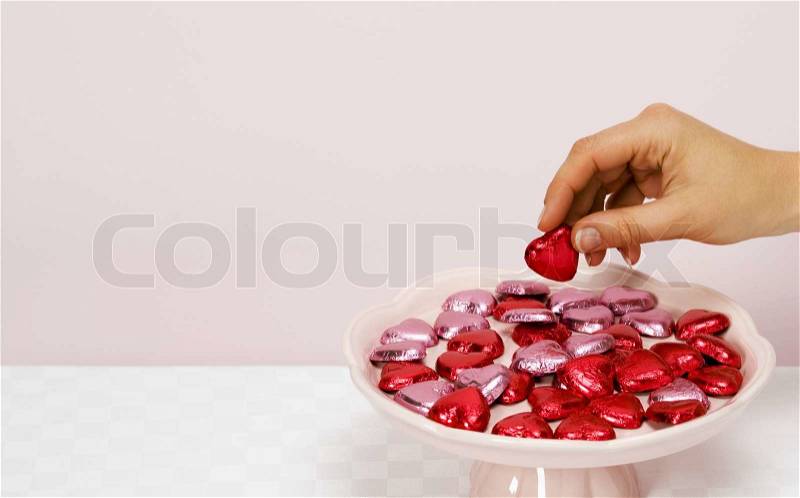 Hand with heart-shaped candies, stock photo