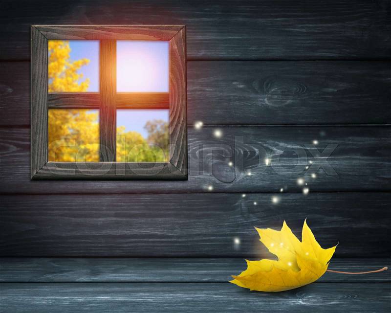 Room interior with window on dark wooden wall background and autumnal yellow maple leaf lying on table and shiny sparkles flying outside. Autumn sunny day. Empty space for your decoration, stock photo