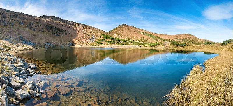 Panorama of mountains lake with reflection in blue water, morning light and shining sun, stock photo