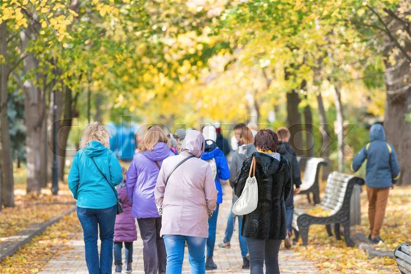 Crowd of people walking in the autumn city park, stock photo