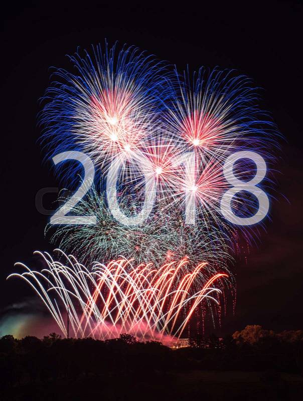 Happy New Year 2018 with colorful sparklers. The letters 2018 are integrated into the fireworks on black background with trees at the bottom, stock photo