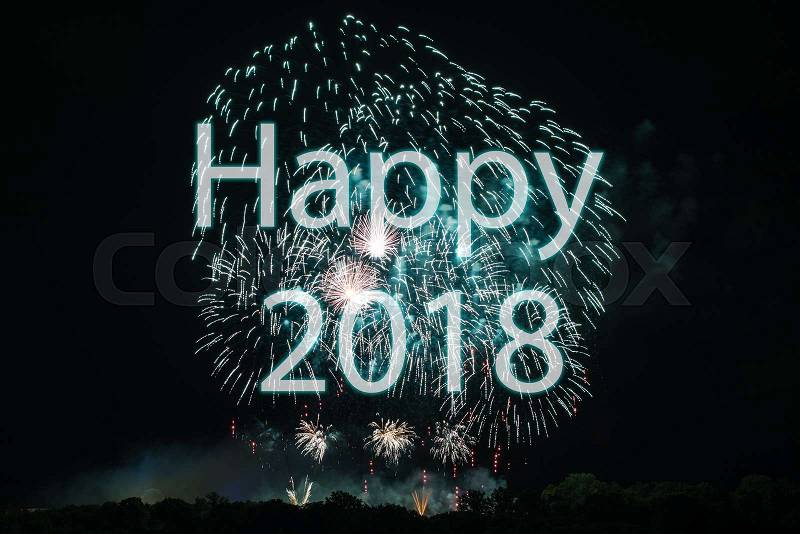 Happy New Year 2018 with colorful sparklers. The words Happy 2018 are integrated into the fireworks on black background with trees at the bottom, stock photo