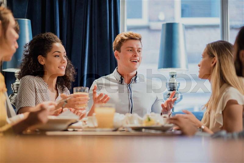 Coworkers are enjoying breakfast together in a restaurant before going to work. , stock photo